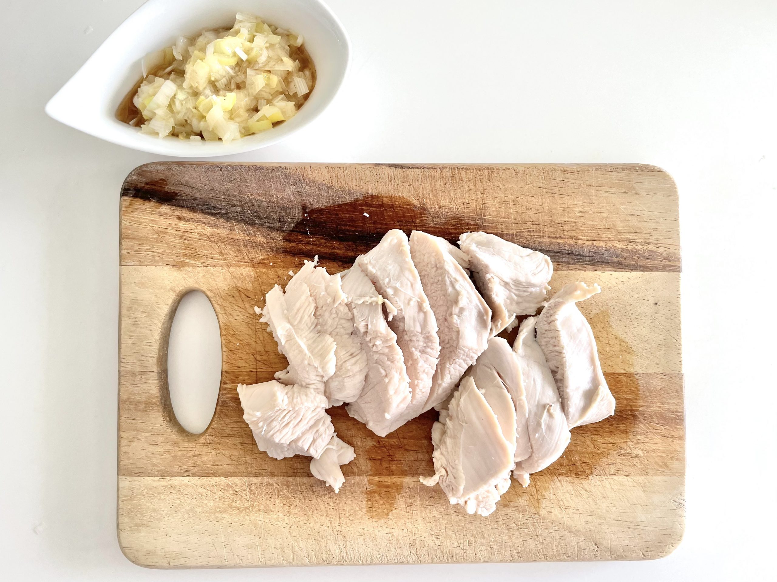 ネギがしんなりしたらソースは完成。蒸し鶏を鍋から取り出し、食べやすい大きさにカットしてネギソースをかけて完成。